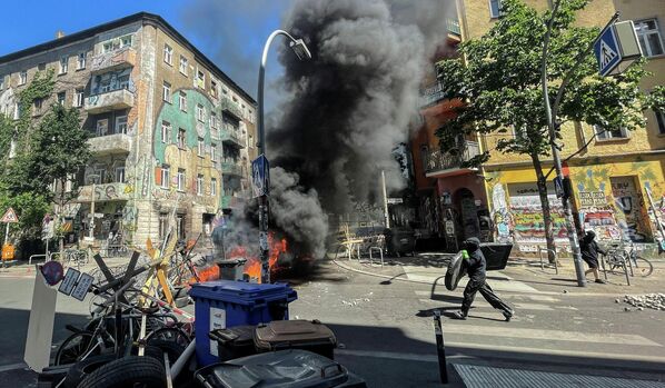Мужчина бежит к горящим баррикадам на улице Ригер в Берлине, Германия. 16 июня 2021 года