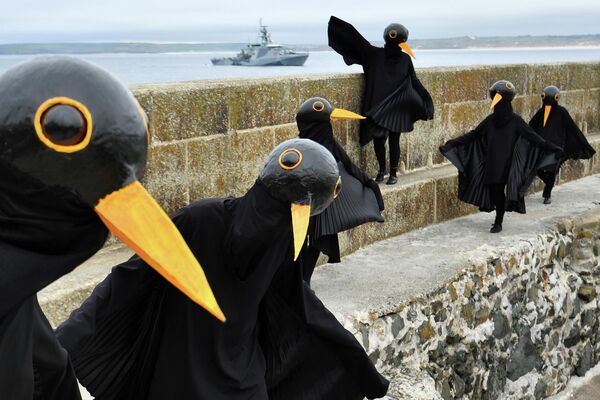 Экоактивисты, одетые как черные птицы, протестуют в Сент-Айвсе, Великобритания