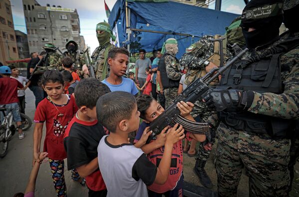 Палестинские мальчики держат автомат, принадлежащий члену бригады Изз ад-Дин аль-Кассамв городе Газа