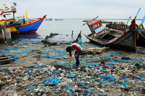 Мусорщик роется в мусоре, который выбросило на берег в прибрежной деревне в Локсеумаве, индонезийская провинция Ачех