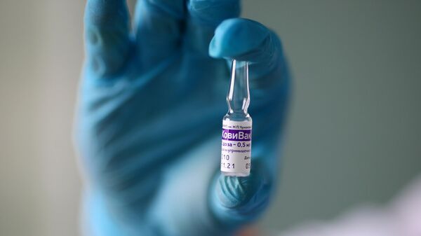 Медицинский работник держит в руках ампулу с вакциной против короновирусной инфекции КовиВак