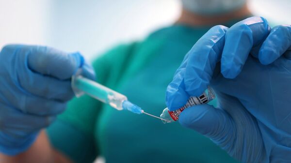 Медицинский работник набирает в шприц вакцину