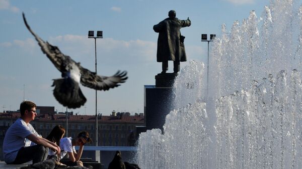 Молодые люди сидят у фонтана возле Финляндского вокзала в Санкт-Петербурге