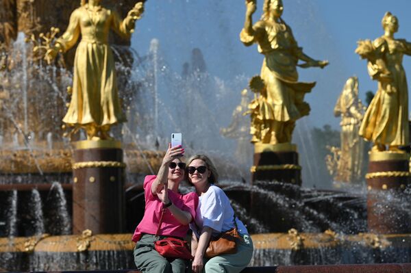 Девушки отдыхают в жаркую погоду у фонтана Дружба народов на ВДНХ