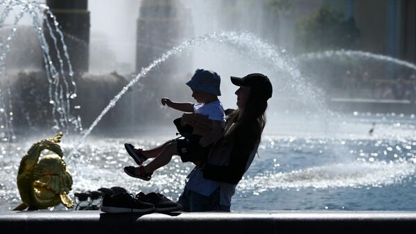 Женщина с ребенком в жаркую погоду у фонтана Дружба народов на ВДНХ