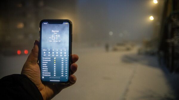 Мужчина демонстрирует мобильный телефон с информацией о прогнозе погоды 