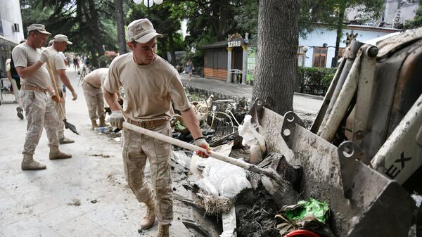 Мужчины очищают тротуар во время ликвидации последствий наводнения в Ялте