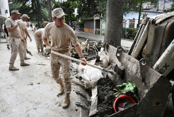 Мужчины очищают тротуар во время ликвидации последствий наводнения в Ялте
