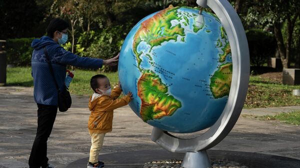Женщина с ребенком у глобуса в парке в Ухани, Китай