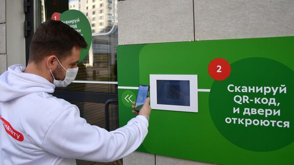 Молодой человек в защитной маске сканирует QR-код с помощью смартфона на входе в магазин