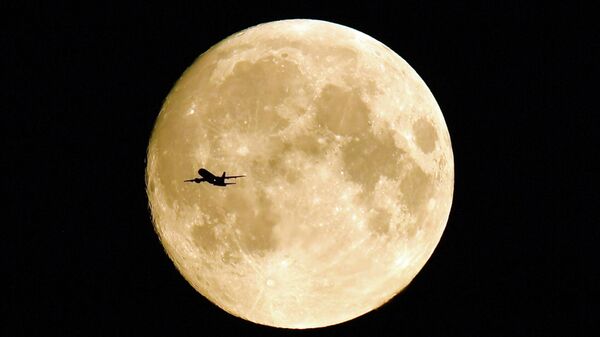 Летящий самолет на фоне полной Луны