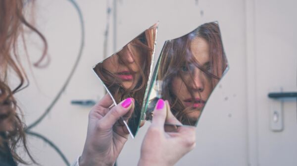Девушка смотрится в разбитое зеркало