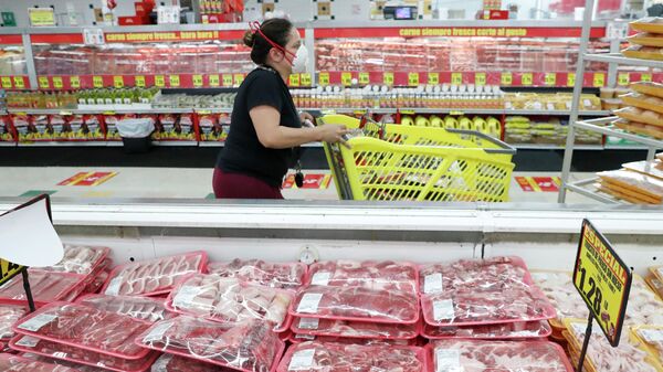 Покупательница в маске проходит через мясные ряды в продуктовом магазине