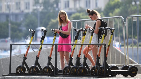 Девушки берут на прокат электросамокаты на набережной Москвы-реки в ЦПКиО имени Горького в Москве