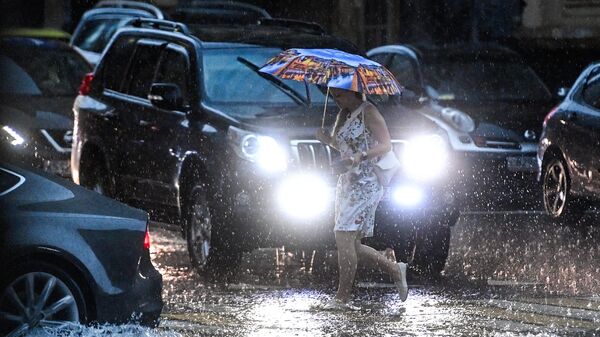 Девушка переходит дорогу на одной из улиц в Москве во время дождя