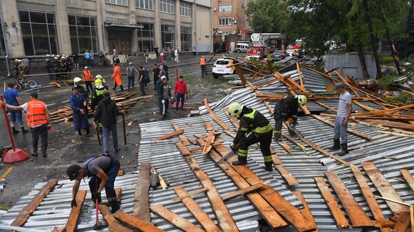 Спасатели убирают фрагменты металлического шифера и деревянных перекрытий обрушившейся из-за сильного ветра части крыши здания на улице Правды в Москве.