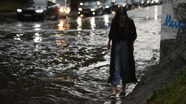 Девушка идет по одной из улиц в Москве во время дождя