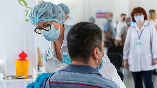 Медицинский работник во время вакцинации трудовых мигрантов в миграционном центре в деревне Сахарово