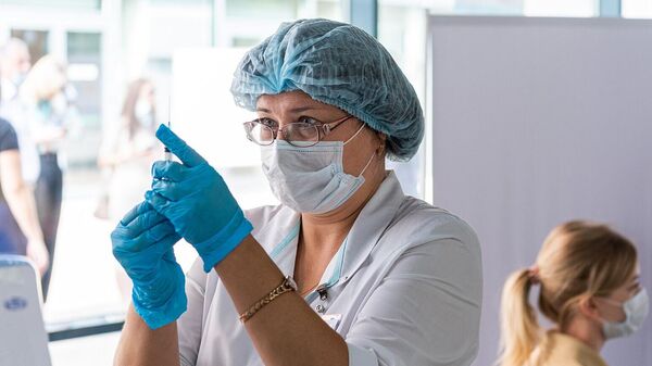 Медицинский сотрудник наполняет шприц вакциной