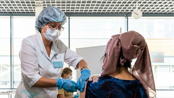 Медицинский работник во время вакцинации трудовых мигрантов в миграционном центре в деревне Сахарово