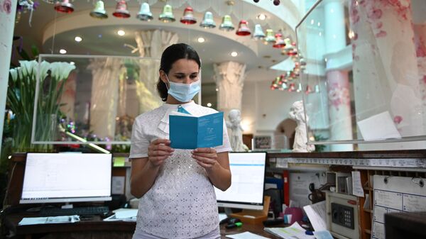 Сотрудница санатория проверяет сертификат о вакцинации от CoVID-19 у гостьи перед заселением в номер 