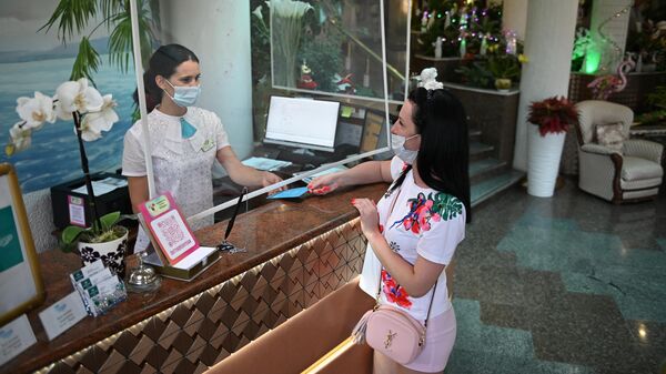 Сотрудница санатория проверяет сертификат о вакцинации от CoVID-19 у гостьи перед заселением в номер