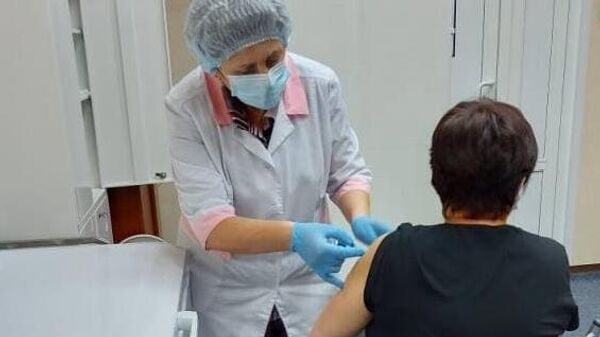 Медицинский работник проводит вакцинацию жительницы Хабаровска против коронавируса