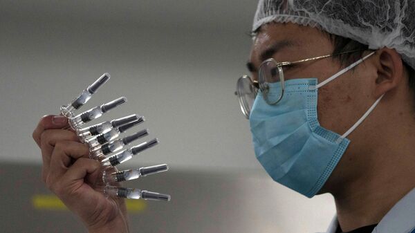 Сотрудник проверяет шприцы с вакциной против вируса SARS CoV-2 на заводе в Пекине