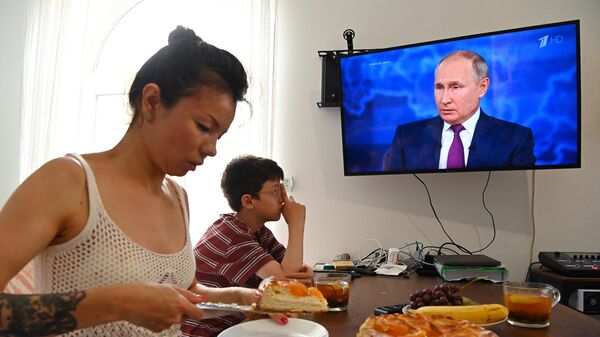 Женщина с ребенком смотрят трансляцию прямой линии с президентом РФ Владимиром Путиным