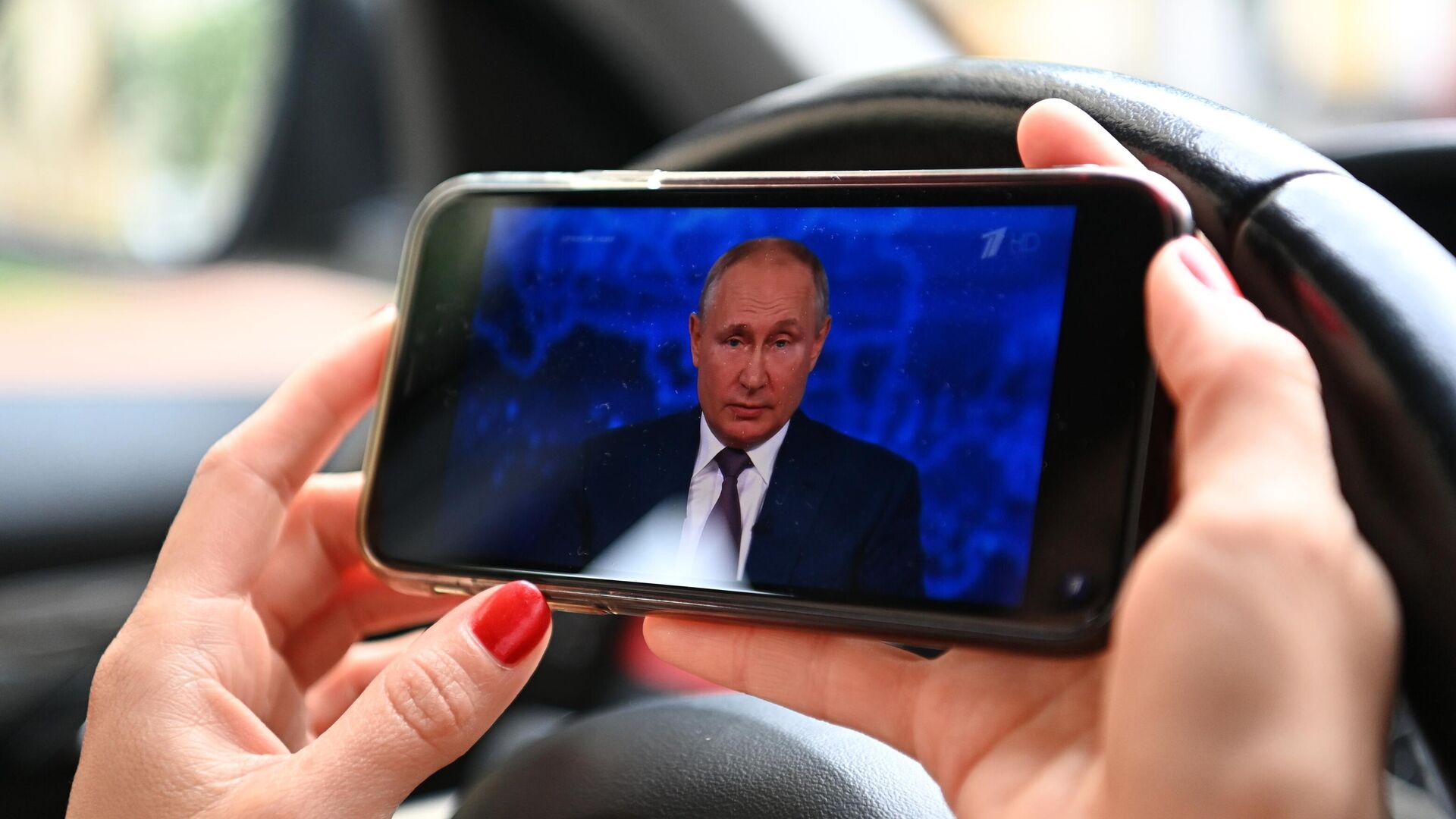 Женщина смотрит трансляцию прямой линии с президентом РФ Владимиром Путиным - РИА Новости, 1920, 06.07.2021