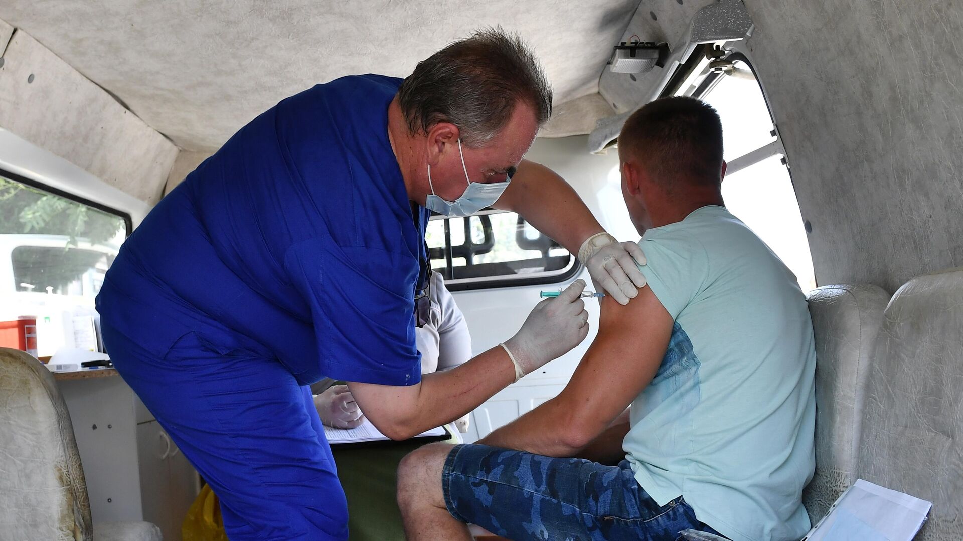 Медицинский сотрудник проводит вакцинацию от COVID-19 мужчине в мобильном пункте вакцинации - РИА Новости, 1920, 19.10.2021