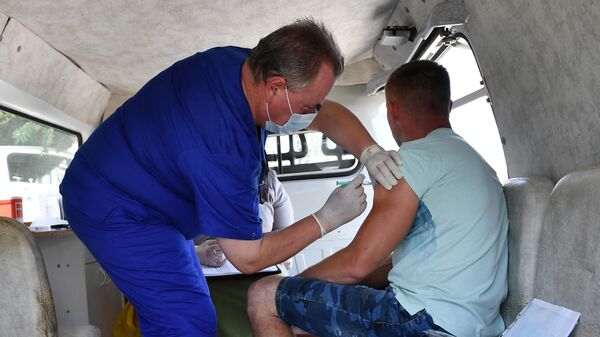 Медицинский сотрудник проводит вакцинацию от COVID-19 мужчине в мобильном пункте вакцинации