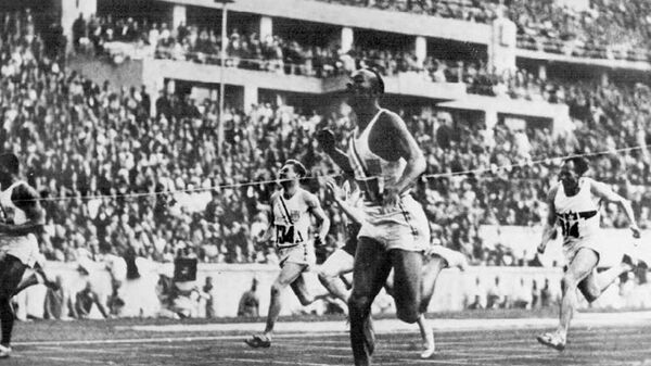 Американский атлет Джесси Оуэнс пересекает финишную черту в забеге на 100 метров на Олимпиаде 1936 года в Берлине