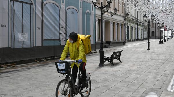 Курьер службы доставки Яндекс Еда едет по Столешникову переулку в Москве