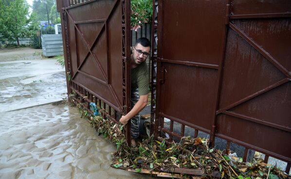 Мужчина убирается во дворе своего подтопленного дома в Хостинском районе Сочи