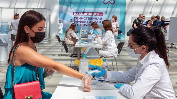 Медицинский сотрудник измеряет температуру женщине перед вакцинацией в центре вакцинации от COVID-19 в Гостином дворе в Москве