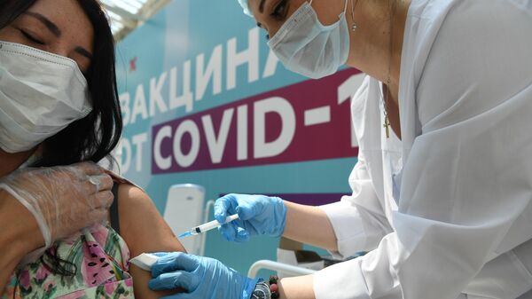 Медицинский сотрудник делает прививку посетителю в центре вакцинации от COVID-19 в Гостином дворе в Москве