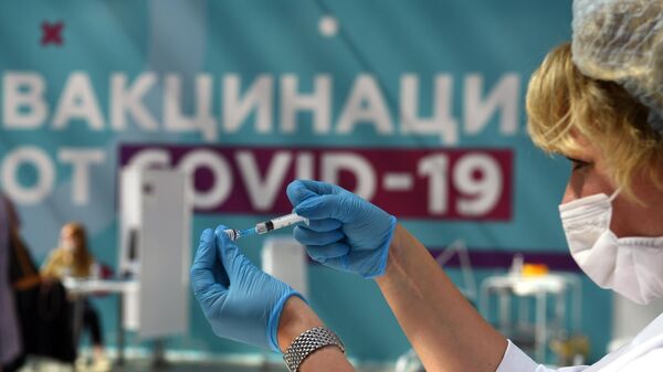 Медицинский сотрудник готовится сделать прививку посетителю в центре вакцинации от COVID-19 в Гостином дворе в Москве