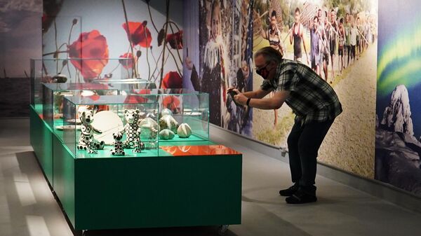 Посетитель фотографирует на мобильный телефон один из экспонатов на выставке Коллекция впечатлений. Фотографы и дизайнеры о путешествиях в Москве
