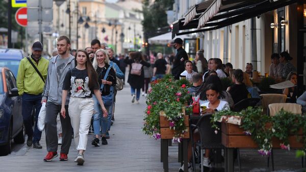 Прохожие идут мимо летней веранды кафе в Москве