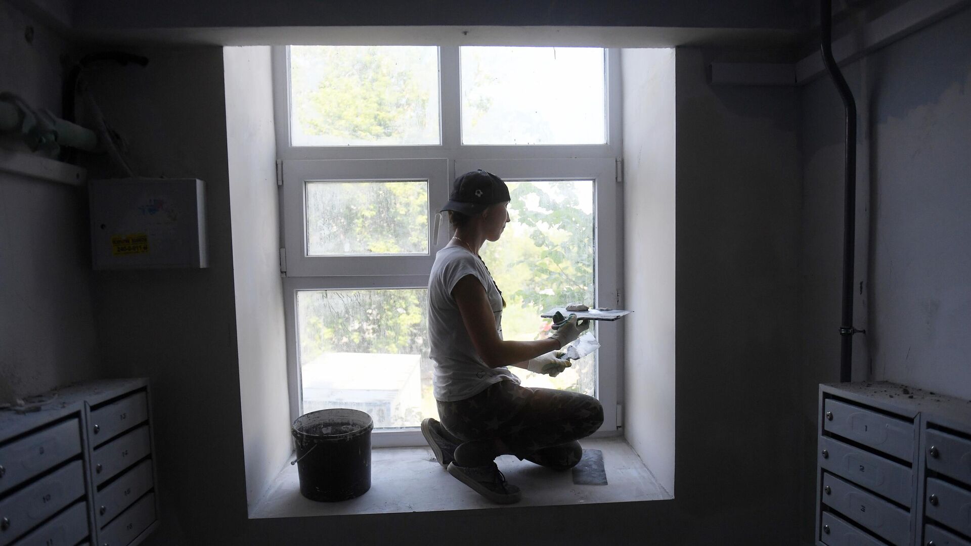 Маляр шпаклюет окно во время капитального ремонта в подъезде жилого дома - РИА Новости, 1920, 20.03.2023