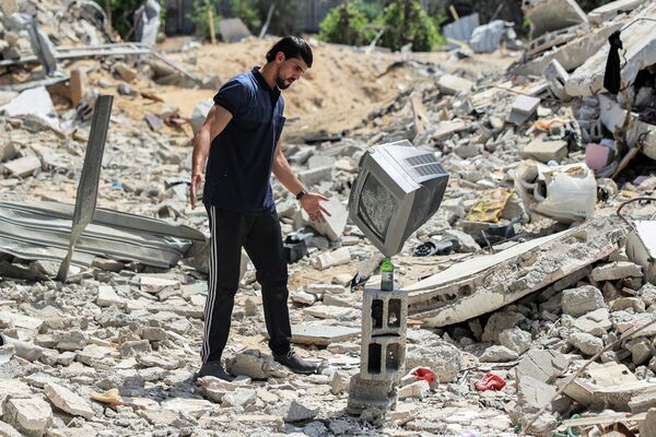 Палестинский художник-постановщик демонстрирует свои навыки балансирования предметов друг на друге на развалинах домов