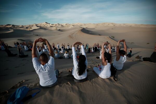 Люди принимают участие в 6-м ежегодном собрании по йоге в дюнах Самалаюка, на окраине Сьюдад-Хуареса, Мексика