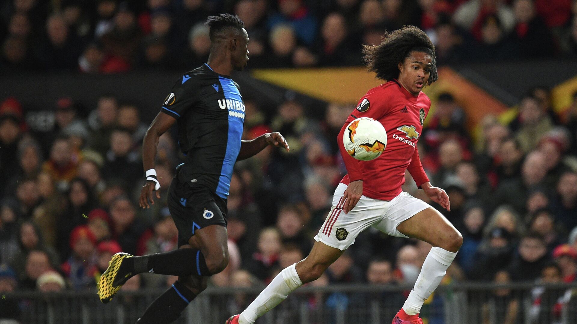 Club Brugge's Ivorian defender Odilon Kossounou (L) vies with Manchester United's Dutch midfielder Tahith Chong during the UEFA Europa League round of 32 second leg football match between Manchester United and Club Brugge at Old Trafford in Manchester, north west England, on February 27, 2020. (Photo by Oli SCARFF / AFP) - РИА Новости, 1920, 09.07.2021