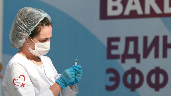 Медицинский работник держит в руках шприц с вакциной 