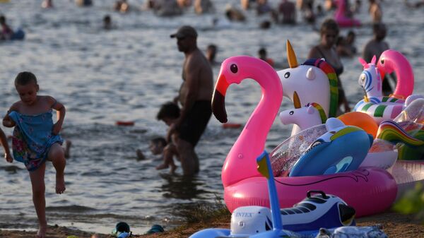 Люди отдыхают на пляже на берегу Белого озера на территории природно-исторического парка Косинский в Москве