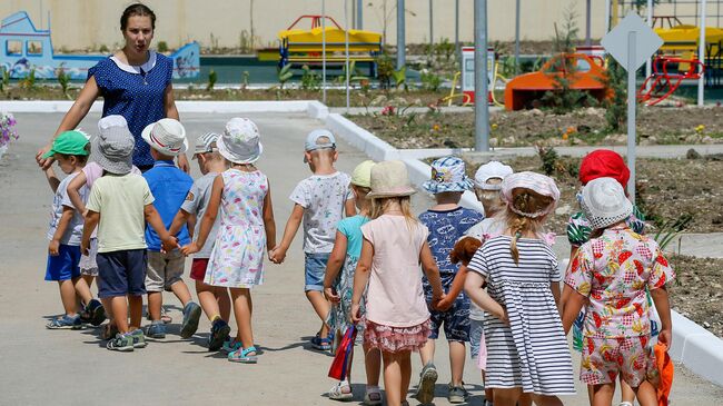 Дети с воспитателем на прогулке в детском саду