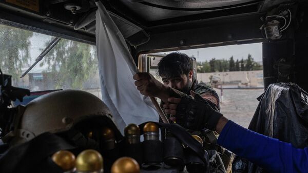Сотрудник афганского спецназа конфискует флаг талибов*