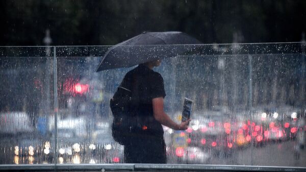 Мужчина под зонтом на одной из улиц в Москве