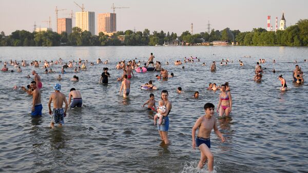 Люди купаются в Белом озере на территории природно-исторического парка Косинский в Москве